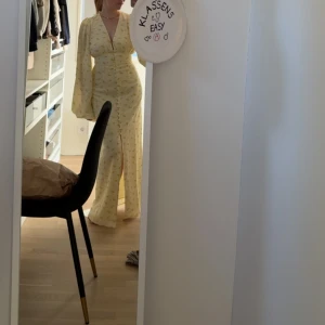 Adoore Positano gul långklänning - Superfin oanvänd långklänning från Adoore i pastellgul med små blommor, v-ringning och knappar framtill. Klänningen säljs inte längre i denna färg på hemsidan. 