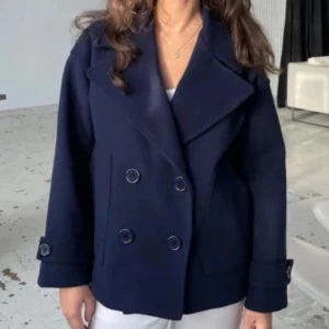 Marin blå kappa - Stilren marin blå kappaj med dubbelknäppning och bred krage. Jackan har långa ärmar och dekorativa knappar vid ärmsluten. Nypris 750kr.