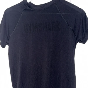 Svart Gymshark t-shirt XS - Svart t-shirt från Gymshark i storlek XS. T-shirten har korta ärmar, rund halsringning och diskret Gymshark-logga framtill. Tillverkad i ett stretchigt och lätt material som passar perfekt till träning. Använd 1-2 gånger