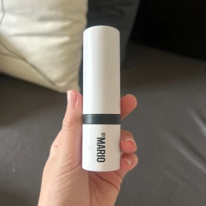 By Mario bronzer stick i brun nyans - Säljer en bronzer stick från By Mario i en snygg brun nyans. Kommer i en stilren vit hylsa med svart detalj, perfekt för att skapa konturer och värme i ansiktet. Enkel att applicera tack vare den krämiga formulan och smidiga stickformatet.