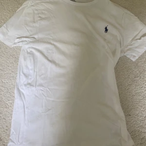 Polo Ralph Lauren T-shirt - Säljer en Polo Ralph Lauren tröja. Den är vit och har ett svart märke. Den har två hål under bägge armhålor (skriv för bild på detta) förutom det är den i mycket bra skick. 