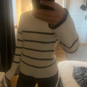 Randig stickad tröja från Anna Field - Säljer en vit stickad tröja från Anna Field i storlek XS. Tröjan har svarta horisontella ränder, rund hals och långa ärmar. Den är ribbstickad och har en klassisk, lite loose passform som är superenkel att styla till jeans eller kjol. Den har används fåtal gånger men har ett hål i armhålan på tröjan 💞