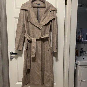 Filippa K kappa  - Jättefin lång kappa i beige från Filippa K. Nypris är cirka 8000kr. Den är använd men inget man märker. Storleken är M. 80% bomull, 20% polymid