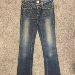 Blå bootcut jeans  - Snygga blå lågmidjade jeans med bootcut passform. Klassisk femficksmodell med bälteshällor och dragkedja. Jeansen har en något ljusare tvätt på låren och raka bakfickor. Perfekta för en avslappnad och trendig look. Midja rakt över: 36cm Lår: 22cm Innerben: 81cm