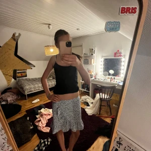 Blommig volangkjol från UNIQ YOUNG - Supersöt kort kjol från UNIQ YOUNG med blått och lila blommönster på vit botten. Kjolen har volangkant nertill och resår i midjan för skön passform. Perfekt för dig som gillar en feminin och fräsch stil! Passar de med storlek XS, S oxå