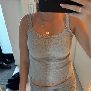 Grå ribbad linnetopp med spets - Supersöt grå ribbad linnetopp med spetskant och liten rosett framtill. Toppen är från hm i storlek S 