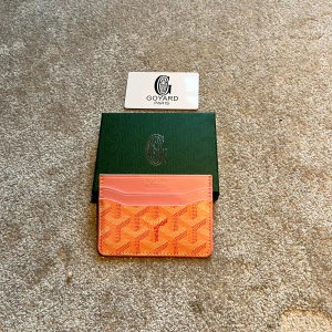 Rosa korthållare från G - Säljer en snygg korthållare från G i rosa och orange med deras ikoniska mönster. Korthållaren har flera fack för kort och är tillverkad i skinn med ett mönstrat tygparti. Perfekt för dig som vill ha något både stilrent och färgglatt i fickan.