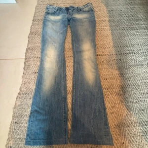 LÅGMIDJADE Blå bootcut jeans med detaljer - Snygga lågmidjade ljusblå bootcut jeans med coola detaljer på bakfickorna. Jeansen har klassisk femficksdesign, låg midja och dekorativa nitar på bakfickorna. ❤️❤️