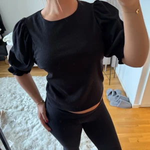 Svart blus med puffärmar från Lindex - Svart blus från Lindex med puffiga trekvartsärmar och rund halsringning. Mycket bra skick! 