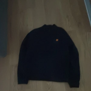 Svart Nike sweatshirt i storlek L i barn storlek  - Svart sweatshirt från Nike i storlek L med enkel design och liten orange Nike-logga på bröstet. Tröjan har rund hals och långa ärmar, perfekt för en clean och sportig look. Materialet är mjukt och skönt, passar till chill eller träning.