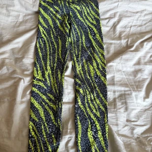 Zebramönstrade leggings i neon och svart - Snygga leggings med zebramönster i neon-gult och svart. De är tajta och stretchiga, perfekta för dig som vill sticka ut. Materialet känns mjukt och följsamt mot huden. Passar perfekt till träning!