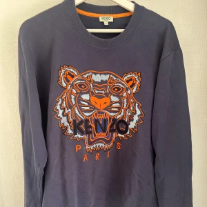 Kenzo sweatshirt med tigerbrodyr - Mörkblå sweatshirt från Kenzo med ikonisk tigerbrodyr i orange, grått och svart framtill. Nypris 2400kr.