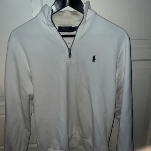 Vit half zip tröja från Polo Ralph Lauren - Vit långärmad tröja från Polo Ralph Lauren med klassisk broderad logga på bröstet. Tröjan har en snygg half zip-dragkedja och hög krage. Perfekt för dig som gillar stilrena och tidlösa plagg. Pris kan diskuteras.