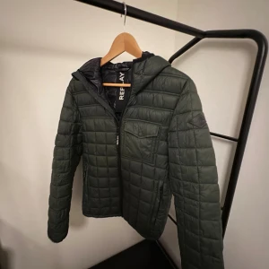 Grön quiltad pufferjacka från Replay - Snygg mörkgrön pufferjacka från Replay med huva och quiltad design i ett riktigt bra skick. Grym jacka för hösten, våren, sommaren samt till början och slutet av vintern. Nypris: 2000kr, mitt pris: 800kr