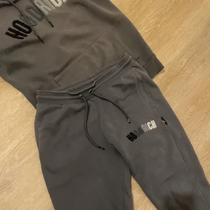 Grå hoodie från Hoodrich med brodyr - Säljer en grå hoodie från Hoodrich i storlek S. Tröjan har broderad HOODRICH-logga i olika grå nyanser på bröstet, huva med dragsko och en stor magficka. Mjuk insida och klassisk streetwear-look, perfekt för chill dagar.[ÄKTA]