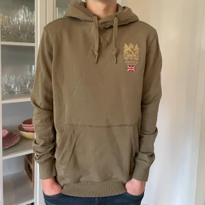 Olivgrön hoodie från Morris - M - Jag säljer den här riktigt fina Morris hoodien. Den är använd men fortfarande i bra skick utan skador. Den är i storlek M men passar även S. Tveka inte att höra av er!