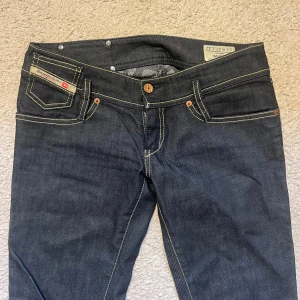 Mörkblå Diesel Larkee jeans - Snygga mörkblå Diesel Larkee jeans med raka ben och kontrasterande gula sömmar. Säljer pga dom är för små för mig. Helt oanvända men köpta på sellpy. Skriv för fler bilder!