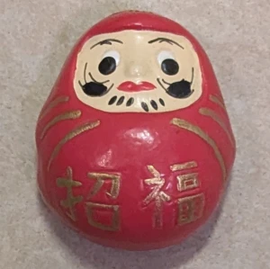 Daruma kylskåpsmagnet - Unik Daruma kylskåpsmagnet i rött med japanska tecken. Magneten är i gott skick och fungerar utmärkt för att fästa lappar eller bilder på kylskåpet. Perfekt som dekorativ detalj eller present. Inga synliga defekter eller slitage.