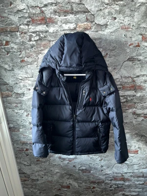 Ralph Lauren Jacka - Mycket fint skick, inga defekter. Storlek 14-16 junior sitter som XS, passar dig som är mellan 160-170cm ungefär. Nypris ca 4000kr. Modellen är 185 cm, 79 kg. Självklart äkta - Kolla bara recensionerna och qr-koden! Passar bra nu till vintern. Skriv för mer information!🤝