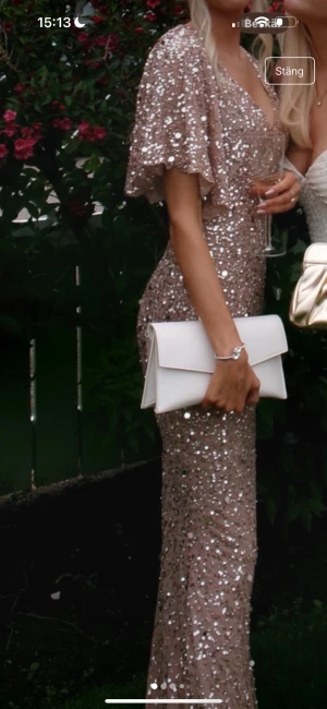 Champagnefärgad glittrig långklänning - Champagnefärgad långklänning med v-ringning och vida korta ärmar. Klänningen är täckt av glittriga paljetter och har en figurnära passform. Perfekt för bal eller student. Materialet är troligtvis polyester med paljettöverdrag för extra glamour. Har tappat en del paljetter ( se bild ) längst ner Xxs/xs