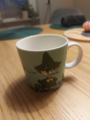 Arabia Muminmugg Snufkin - Fin Arabia Muminmugg med Snufkin-motiv. Muggen är i mycket gott skick utan synliga repor eller nagg. Tål diskmaskin, mikrovågsugn och ugn. Perfekt för samlare eller som present till Mumin-fans.