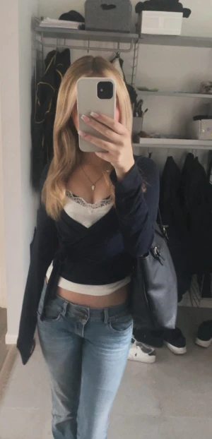 Mörkblå omlottopp från Gina Tricot - Snygg mörkblå omlottopp från Gina Tricot med långa ärmar och knyt i midjan. Toppen är croppad och har en v-ringad design som ger en trendig look. Perfekt att styla med jeans eller kjol för en cool vibe.