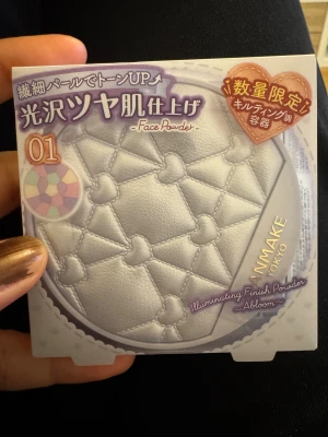 CANMAKE Illuminating Finish Powder - Säljer CANMAKE Illuminating Finish Powder Abloom 01, en ansiktspuder med SPF24 PA++. Pudret har en quiltad design med hjärtformade detaljer och innehåller fem färger för att korrigera hudtonen. Ger en glowig finish med pärlemorskimmer och passar perfekt för att sätta basen.