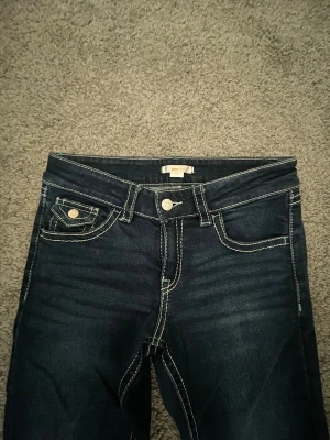 Low bootcut  jeans från Gina Tricot - Snygga mörkblå bootcut jeans från Gina Tricot i storlek 164. Jeansen har kontrasterande vita sömmar, klassiska fem fickor med lock och knapp på bakfickorna, samt knapp och dragkedja framtill. Perfekt passform och supersköna. Jag är 176 och de är även perfekta i längden. Passar bra till alla möjliga färger ❣️
