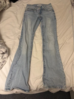 Ljusblå bootcut jeans från Gina Tricot - Säljer ett par ljusblå jeans från Gina som knappt har används. Står att storleken är 32 och måtten är 30cm rakt över och innerbenslängden är 76 cm.