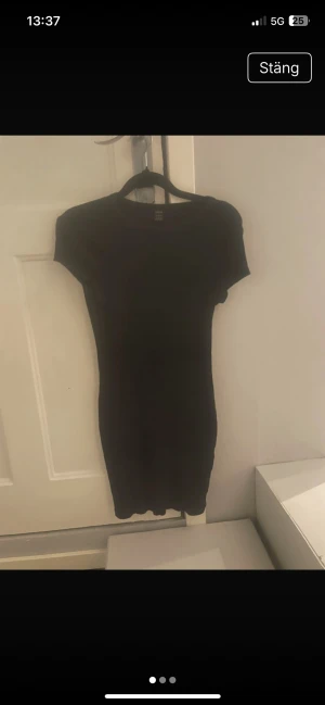 Svart ribbad kortklänning från SHEIN - En svart, tight ribbad kortklänning från SHEIN i storlek M. Klänningen har korta ärmar och rund halsringning, med en enkel och stilren design som sitter figurnära. Perfekt för dig som gillar minimalistisk och clean stil.