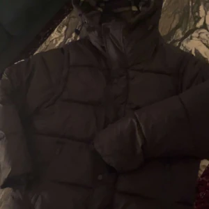 Svart pufferjacka Burberry S - Svart pufferjacka från Burberry med klassisk rutig insida i grått, vitt och rött. Jackan har hög krage, dragkedja och synlig Burberry London England-patch på bröstet. Perfekt för kalla dagar med sin tjocka och quiltade design. Den är i 10/10 skick och endast använd fåtal gånger. Säljer den för att den är för stor 