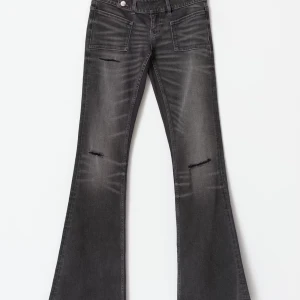 Bootcut svarta jeans med slitningar - Snygga svarta bootcut jeans med slitningar på låren och knäna. Jeansen har framfickor och en cool tvättad look med ljusare partier. Passar dig som gillar en lite edgy stil och vill sticka ut med breda ben och detaljerade slitningar. Använd 1 gång. Säljer då dom var lite för stora. 
