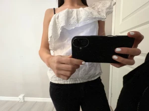 Vit volang topp  - Säljer en vit volang topp,ärmlös på ena sidan perfekt till sommaren och har knappast använd den, har inga skador💗