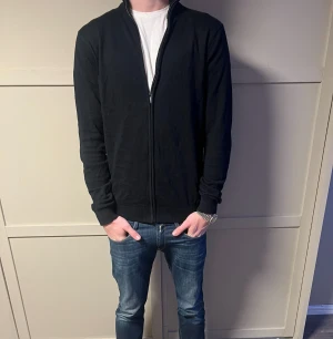 Svart kofta från On Our Terms  - Svart kofta från On Our Terms i storlek M. Tröjan är endast använd någon gång och är som ny. Tröjan har hel dragkedja framtill, ribbade muddar och hög krage. Materialet är mjukt och känns som bomull. Enkel och stilren design som funkar till jeans eller andra byxor.