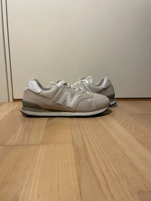 Beige New Balance sneakers - Snygga beige New Balance sneakers med klassisk vit N-logga på sidan. Skorna har ovandel i mocka och mesh, vita detaljer och snörning. Sulan är svart och grå med ENCAP-dämpning för extra komfort. Perfekta för dig som gillar stilrena och bekväma sneakers. Skorna är i storlek 45.5 men sitter som 45.