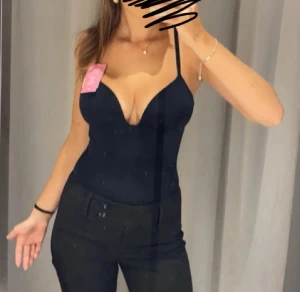 Svart korsett-topp med smala axelband - Säljer en svart body från H&M med vadderade kupor och smala, justerbara axelband. Toppen har en djup v-ringning och figurnära passform som framhäver siluetten. Perfekt för dig som vill ha en stilren och trendig look. Använd kanske 2-3 gånger och säljer då jag knappt använder den