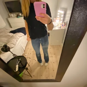 Blå bootcut jeans med hög midja - Säljer ett par snygga blå bootcut jeans med hög midja. Jeansen har klassisk femficksdesign, dragkedja och knapp framtill. Materialet är jeans med lätt tvättad look och de sitter riktigt bra över höfterna och låren innan de blir vidare nedtill.