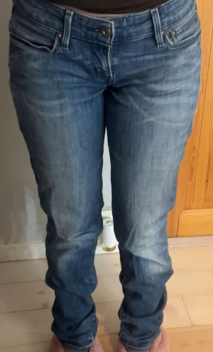 Levi's 505 blå jeans straight fit - Säljer ett par klassiska Levi's 505 jeans i blå tvätt med snygga slitningar. Modellen har rak passform, normal midja och fem fickor. Jeansen är tillverkade i robust denim och har Levi's ikoniska bakfickor med bågmönster och läderpatch i midjan.