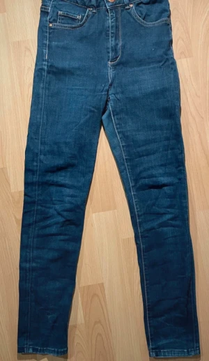 Never Denim blå skinny jeans 27/32 - Mörkblåa högmidjade skinny jeans från Never Denim, raka ben med smal passform. Stretchig material för extra komfort.
