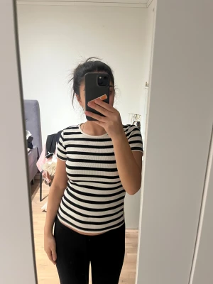 Svartvit randig ribbad topp - Säljer en svartvit randig topp med korta ärmar och rund hals. Toppen är ribbad och har en slim passform som sitter snyggt mot kroppen. Perfekt för dig som gillar en enkel men stilren look.