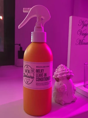 Sol de Janeiro Milky Leave-In Conditioner - Sol de Janeiro Milky Leave-In Conditioner i en orange flaska med vit spraypump. Produkten är en leave-in balsam som återfuktar och skyddar håret mot värme och UV. Flaskan har en modern design och är perfekt för dig som vill ha mjukt och fräscht hår.