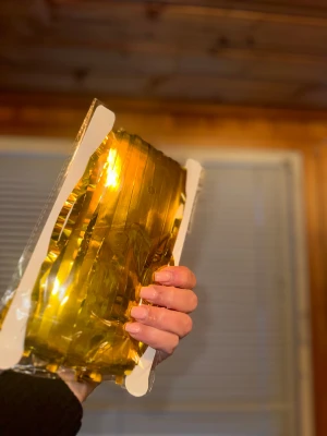 Draperi curtain girlang i guld folie  - Bilden visar ett paket med guldfärgad folie, en dekoration, för fest för födelsedagar, tema piffa upp hemmet innan gästerna ankommer. 2 m lång och 1 m bred. Läggs på vägg eller dörr 🚪 🎉 