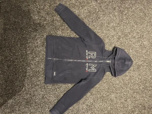Mörkblå hoodie från Race Marine XS - Snygg mörkblå hoodie från Race Marine i storlek XS. Tröjan har huva med snörning, dragkedja framtill och broderade detaljer med koordinater och RM-logga på bröstet. Tillverkad i mjuk bomull, perfekt för chill dagar. Två fickor framtill för extra casual vibe.