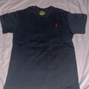 Svart Ralph Lauren t-shirt f Ralph Lauren - Svart t-shirt från Polo Ralph Lauren med röd  märke på bröstet. Storlek M men passar bra på S. Slim fit.