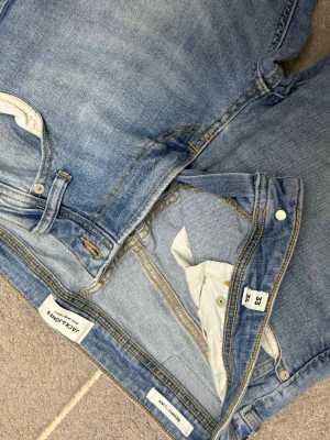 Jack & Jones ljusblå jeans  - Säljer ett par ljusblå  från Jack & Jones. Modellen har klassisk femficksdesign, gul kontrastsöm och bra passform hela vägen ner. Jeansen är tillverkade i stretchigt denim för extra komfort och har en snygg tvättad look.