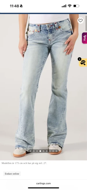 True Religion lågmidjade bootcut jeans - Säljer ett par ljusblå jeans från True Religion med låg midja och bootcut passform. Jeansen har tydliga vita och röda sömmar. Köpta för 2299 kr och använda 1 gång pris går att diskutera❤️💗