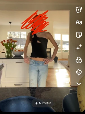 Svart omlott topp med cut out - Trendig svart topp med omlott-detalj och cut out framtill. Toppen är ärmlös och har en asymmetrisk design med en axel. Perfekt för dig som vill sticka ut med en unik och modern look.