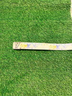 Louise Vuitton vitt bälte med färgglatt mönster - Louise Vuitton bälte i vitt skinn med färgglada L.V-loggor och silverfärgat spänne. Bältet har en klassisk design med exklusiv känsla och passar perfekt för att lyfta din outfit med en lyxig touch.