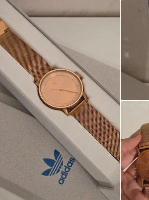 Adidas guldfärgad meshklocka - Stilren klocka från Adidas i guldfärgat rostfritt stål med mesharmband och minimalistisk urtavla. Klockan har en rund form och diskret Adidas-logga på urtavlan. Perfekt accessoar för en trendig look. Fläck vid baksidan. Klockan fungerar ej därav priset men kvalitén är bra