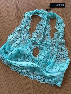 Lounge BH 🩵 - Säljer en ny turkos topp från Lounge Underwear. Toppen är ärmlös och har vackra blommiga spetsdetaljer samt elastiskt band under bysten. Modell Floral Lace Triangle Bralette. Storlek S 🩵